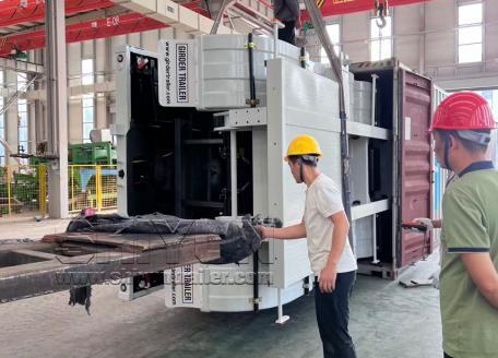 Workers loading trailer section into container