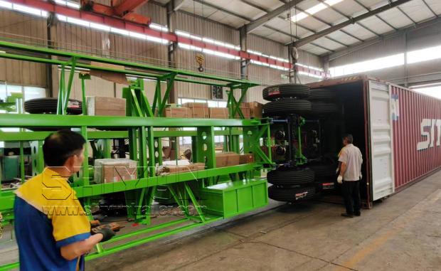 Green trailer being loaded worker supervising